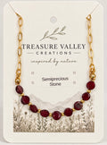 Treasure Valley Creations semiprecious stone necklace with dark red oval beads and gold chain links, displayed on a branded cream-colored backing card.