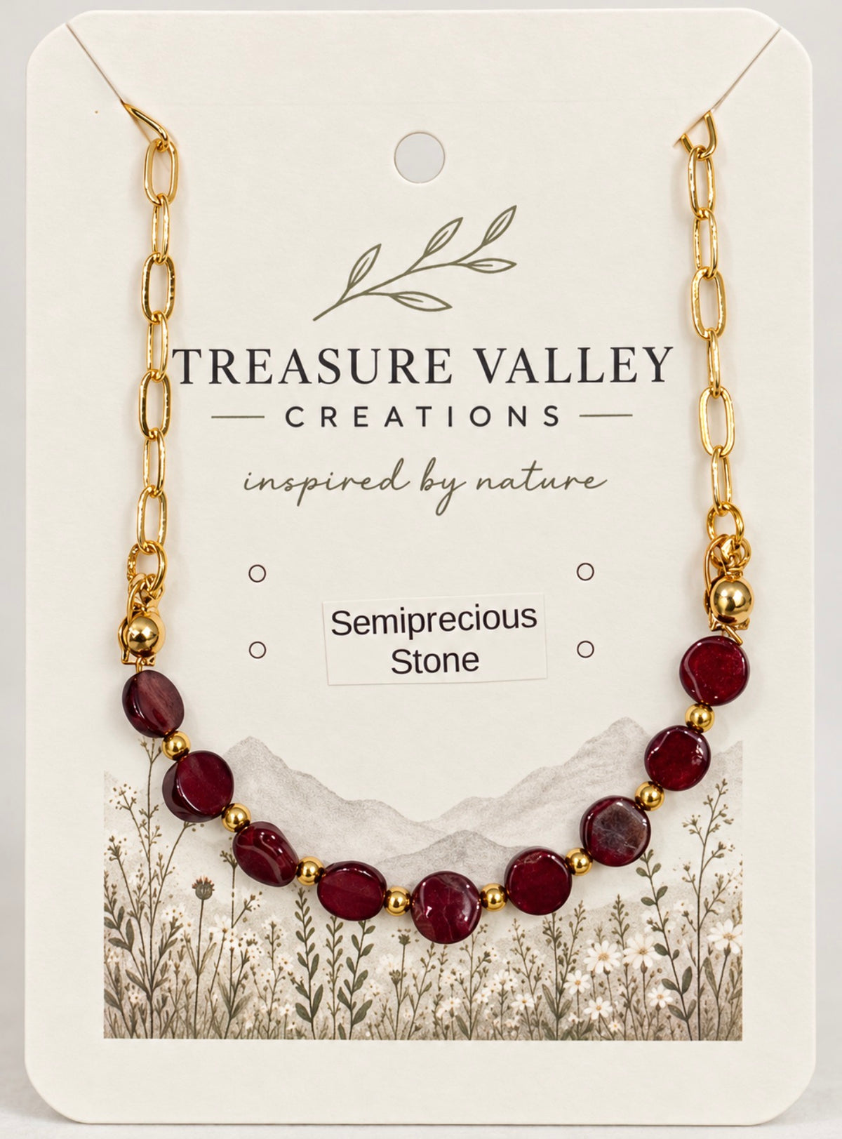 Treasure Valley Creations semiprecious stone necklace with dark red oval beads and gold chain links, displayed on a branded cream-colored backing card.