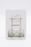A pair of silver hypoallergenic hoop earrings with long chain links, displayed on a white backing card from the brand Treasure Valley Creations. The backing card features a botanical and mountain illustration.