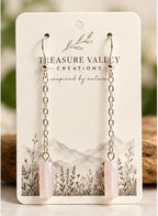 A pair of long dangle earrings with silver-toned chain links and pale pink cylindrical drops, displayed on a white backing card printed with the brand name Treasure Valley Creations.