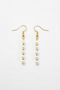 A pair of gold-tone dangle earrings with small white pearl beads, displayed on a clean white background.
