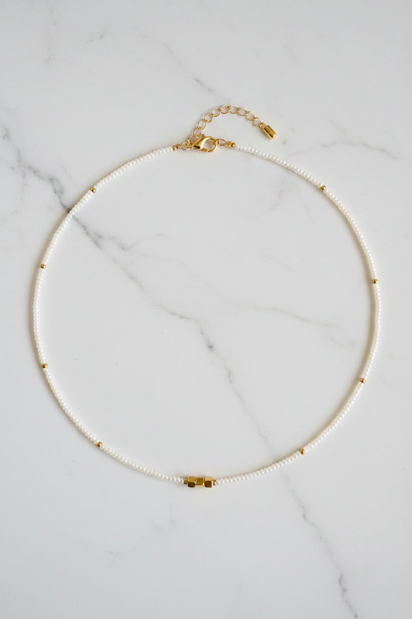 Pearl necklace with gold clasp on a white fabric background