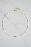 Pearl necklace with gold clasp on a white fabric background