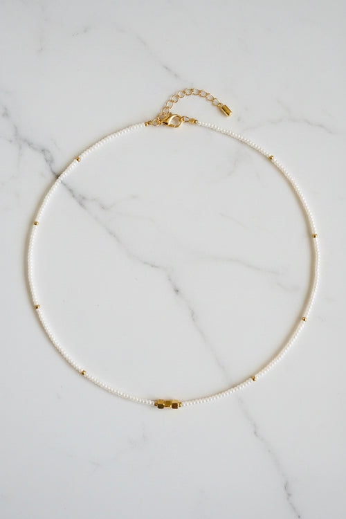 Pearl necklace with gold clasp on a white fabric background