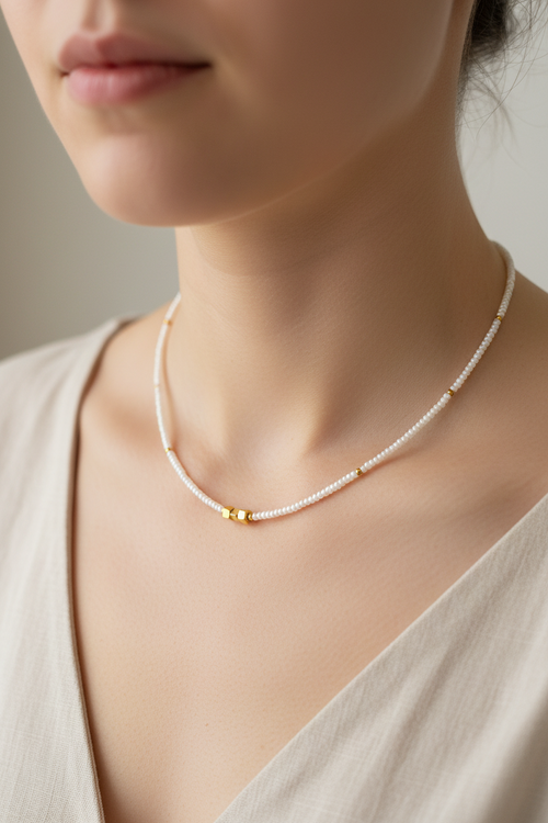 Pearl necklace with gold accents worn by a model against a neutral background