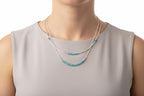 Necklaces with blue beads on a grey shirt