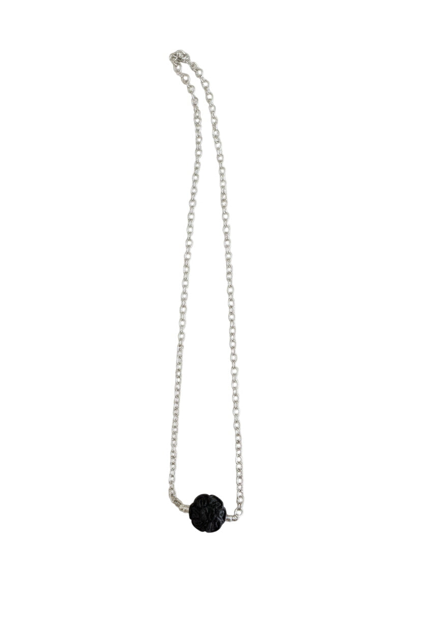 Silver necklace with a black pendant on a marble surface