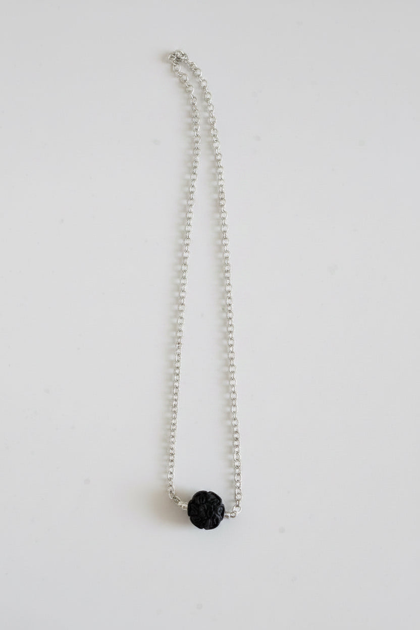 Silver necklace with a black pendant on a marble surface