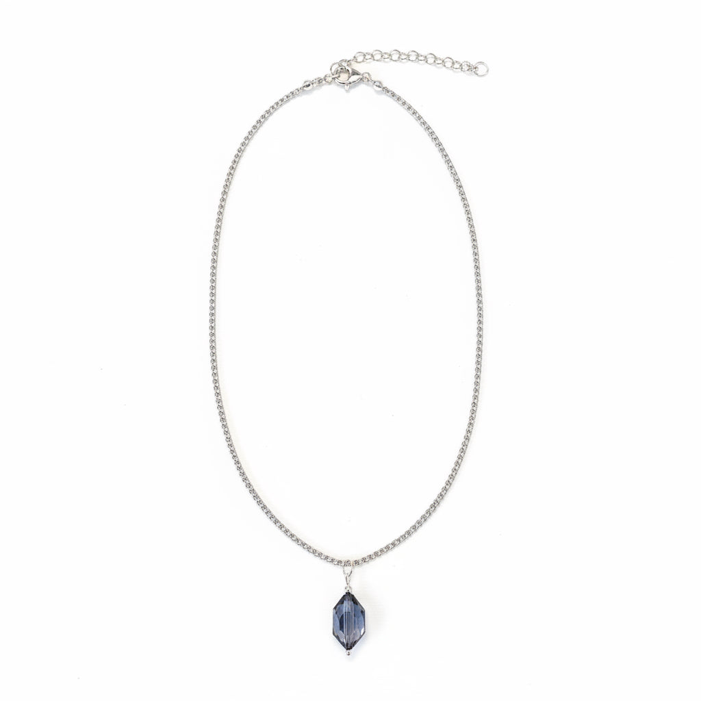 A silver-toned chain necklace with an adjustable clasp and a faceted dark blue teardrop-shaped pendant, shown on a plain white background.