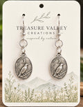 A pair of silver-toned dangle earrings with oval bird medallions and crescent moon details