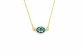 A delicate gold chain necklace featuring an oval-cut teal gemstone pendant with small gold loops on either side, shown against a plain white background.