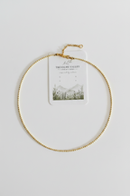 A delicate gold beaded chain necklace with an extender clasp, displayed on a white card from Treasure Valley Creations, set against a clean white background.