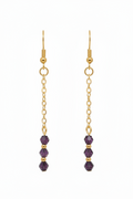 A pair of gold dangle earrings with three faceted purple beads at the bottom, shown against a plain white background.