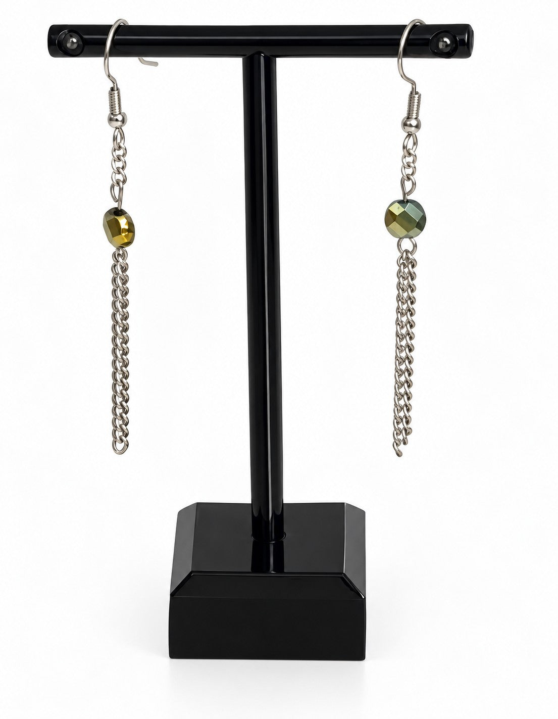 A pair of silver-toned dangle earrings with faceted olive-green beads and chain drops, displayed on a black jewelry stand against a white background.
