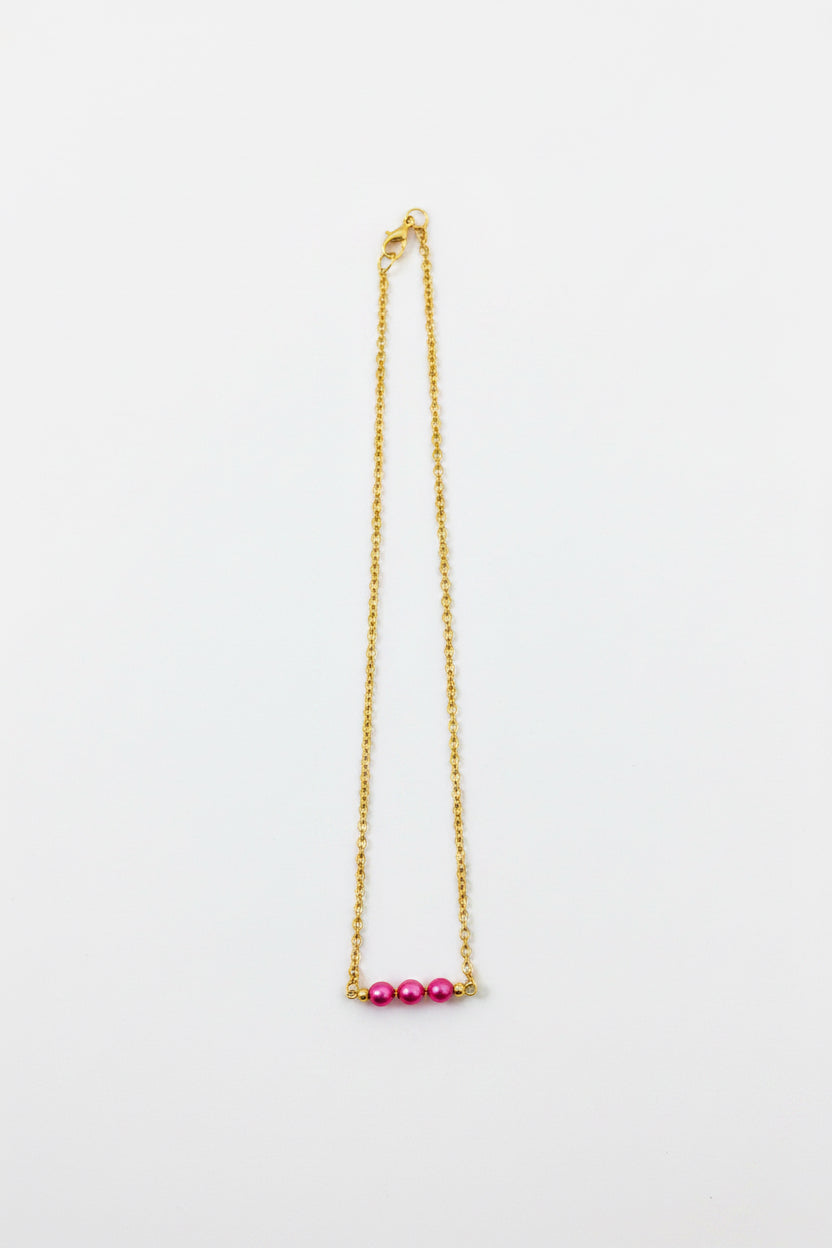 Gold necklace with pink beads on a white background