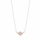 A delicate silver chain necklace featuring a single round, faceted pale pink gemstone pendant held by small silver beads on a white background.