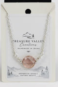 A silver chain necklace with a faceted blush pink gemstone pendant, displayed on its white backing card. The card features the brand name 'Treasure Valley Creations' and a scenic Idaho graphic.