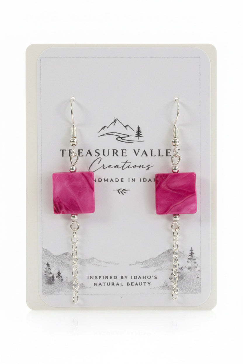 A pair of dangle earrings with square pink marbled beads and silver chain drops, displayed on a white Treasure Valley Creations card.