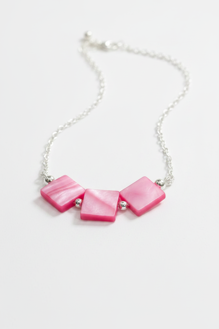 A silver chain necklace featuring three pink mother-of-pearl square beads separated by small silver spacer beads, displayed on a clean white background.