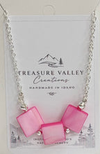 A silver chain necklace with three pink square shell beads, displayed on a white backing card from Treasure Valley Creations.