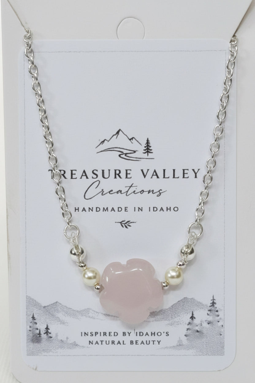 A silver chain necklace with a central pale pink cloud-shaped stone and small pearl-like beads, displayed on a white Treasure Valley Creations card.