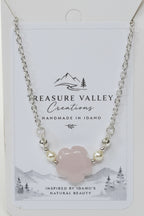 A silver chain necklace with a central pale pink cloud-shaped stone and small pearl-like beads, displayed on a white Treasure Valley Creations card.
