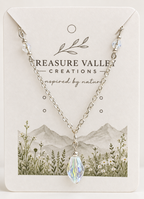A silver chain necklace with a faceted iridescent crystal pendant, displayed on a cream-colored jewelry card from Treasure Valley Creations.