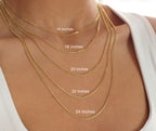 Gold necklaces of different lengths displayed on a person's neck.