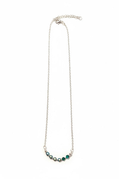 A delicate silver chain necklace featuring a curved row of faceted green gemstones at the center, displayed against a solid white background.