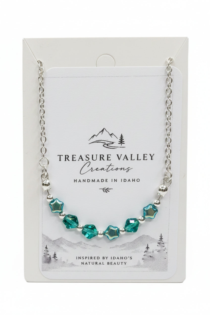 Treasure Valley Creations handmade necklace with faceted green and blue beads on a silver chain, displayed on its white backing card.