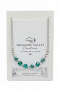 Treasure Valley Creations handmade necklace with faceted green and blue beads on a silver chain, displayed on its white backing card.