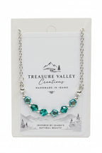 Treasure Valley Creations handmade necklace with faceted green and blue beads on a silver chain, displayed on its white backing card.