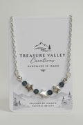 A silver-toned beaded necklace with star and faceted bead accents, displayed on a white Treasure Valley Creations card.