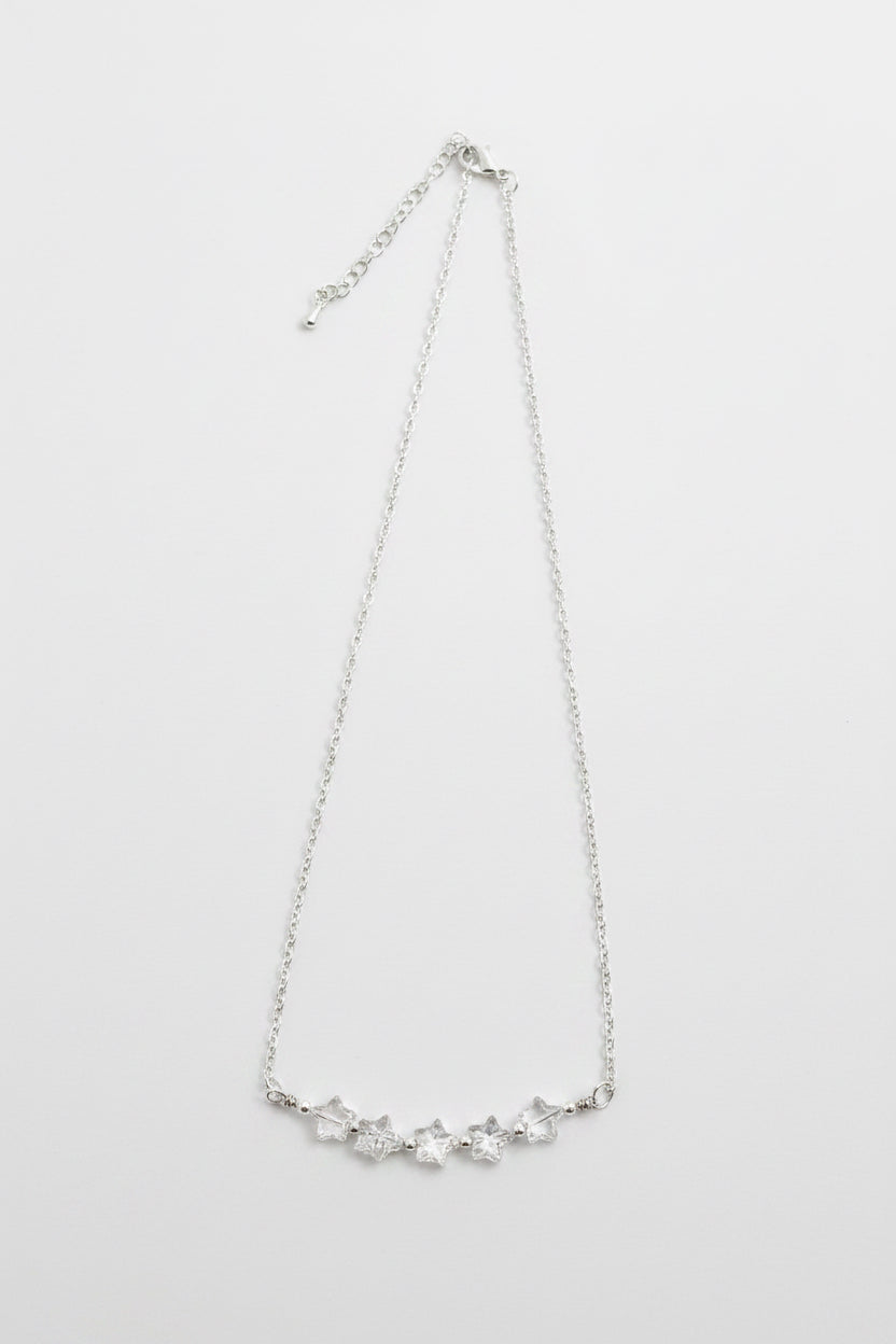 A delicate silver chain necklace featuring a curved bar of small, clear, faceted stones at the center, displayed against a plain light gray background.