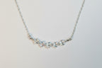 A silver-toned chain necklace featuring a central cluster of clear, faceted crystal beads on a plain light gray background.