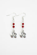 A pair of silver-toned dangle earrings with three small red faceted beads and a swan-shaped charm at the bottom, shown on a plain white background.