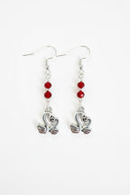 A pair of silver-toned dangle earrings with three small red faceted beads and a swan-shaped charm at the bottom, shown on a plain white background.