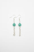 A pair of silver dangle earrings with faceted green beads and dangling chain links, shown on a plain white background.