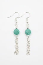 A pair of silver dangle earrings with faceted green beads and dangling chain links, shown on a plain white background.