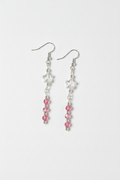 A pair of silver dangle earrings featuring a white star charm, a clear faceted bead, and a vertical strand of pink faceted beads on a light gray background.