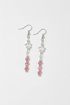 A pair of silver dangle earrings featuring a white star charm, a clear faceted bead, and a vertical strand of pink faceted beads on a light gray background.