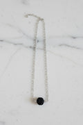 Silver necklace with a black pendant on a marble surface