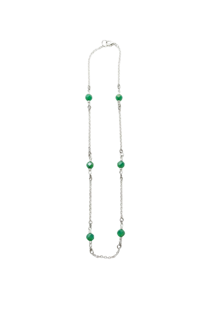 Necklace with green beads on a white fabric background